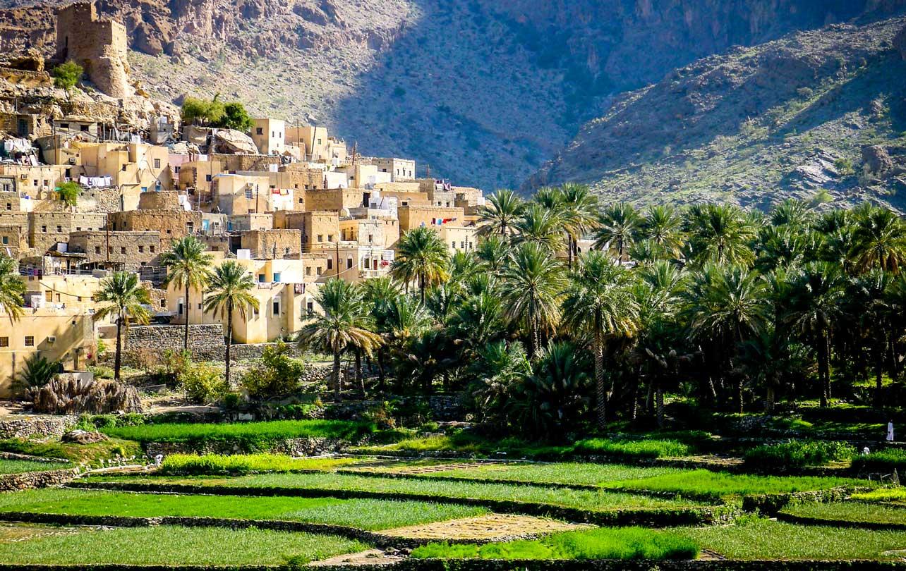 The mountain village of Balad Sayt sits in front of green fields in Wadi Bani Awf, Oman